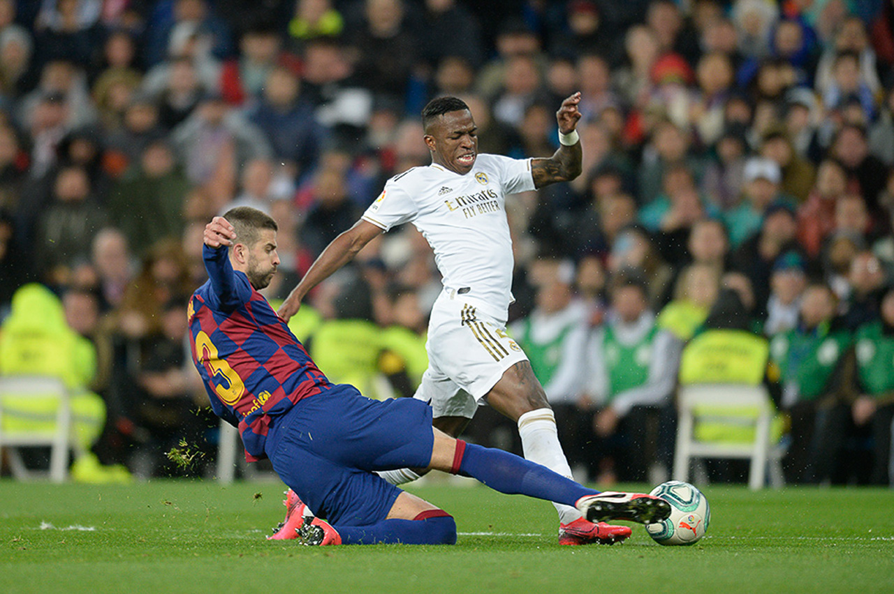 Vinicius Jr y Gerard Piqué disputan el balón durante el derby español.