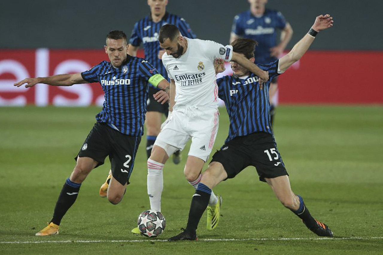 Karim Benzema disputa el balón contra jugadores del Atalanta.