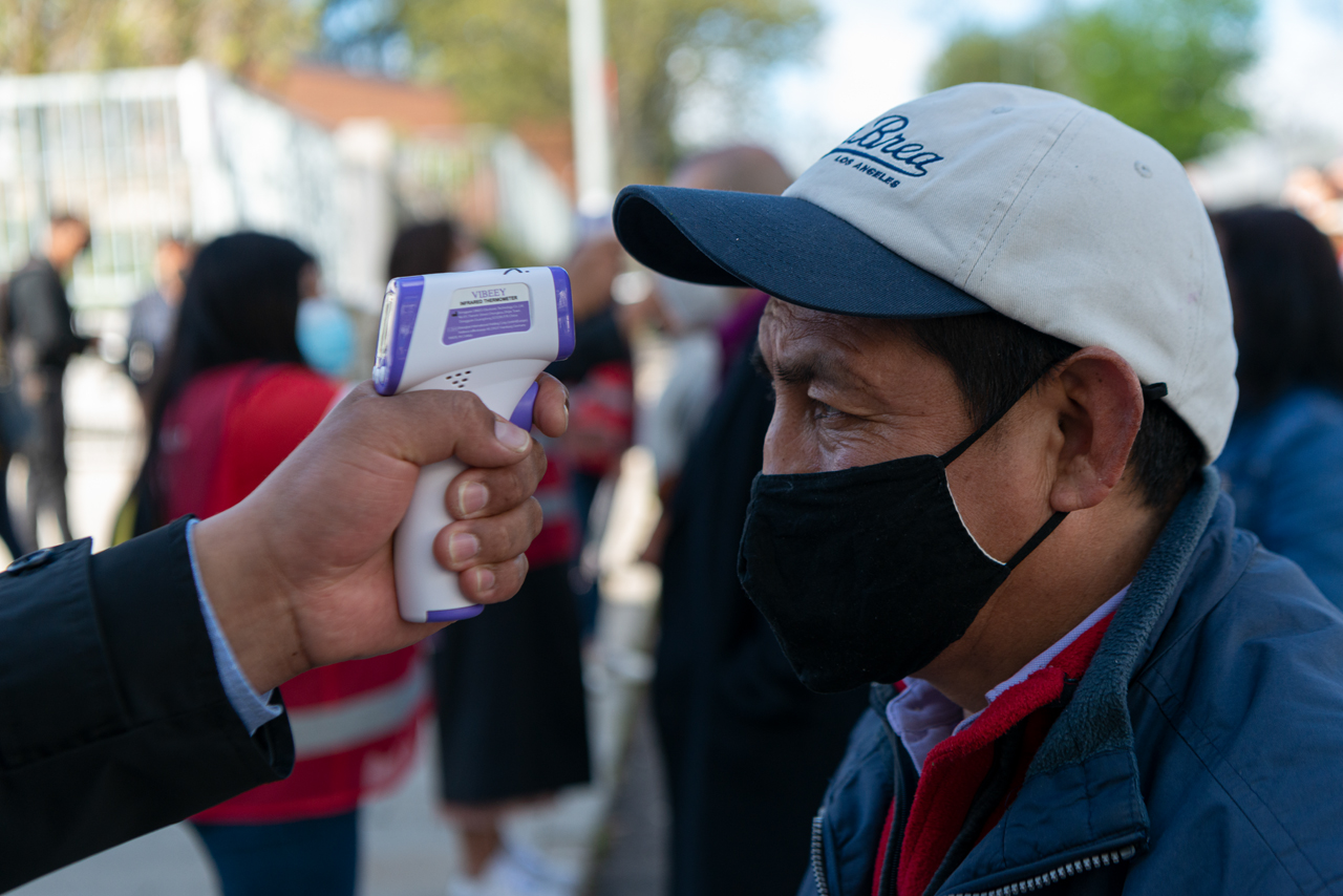 Un ecuatoriano es medido la temperatura previo a entrar a votar porque Ecuador elige a un nuevo presidente.