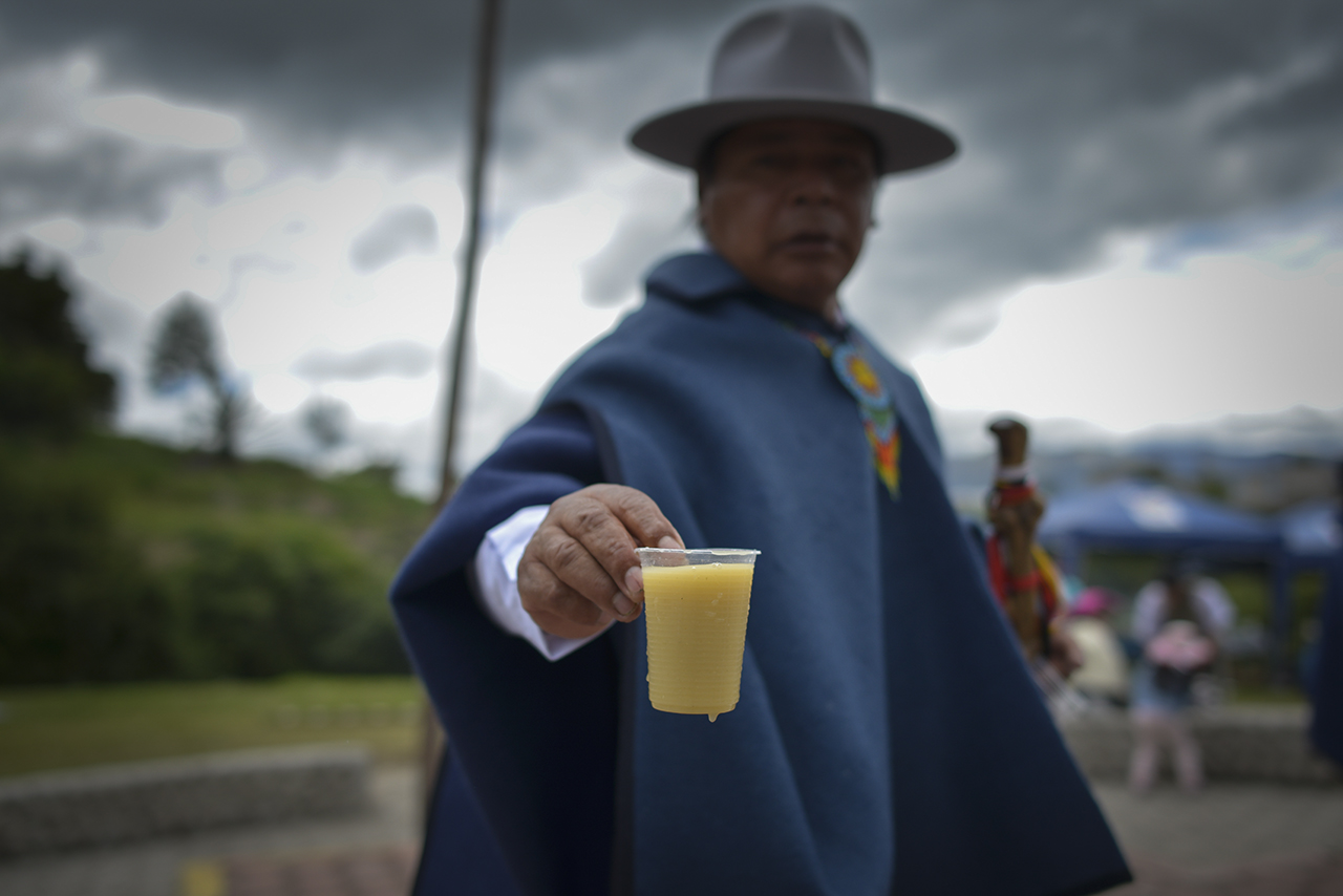 Un Yachak  de Ilumán brinda una chicha de Jora a un visitante durante la fiesta del Inti Raymi que es parte de la historia de Entre dos Tierras. 